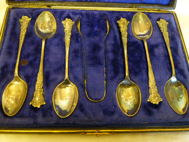 Cased set of six silver plated decorative teaspoons and a pair of sugar tongs