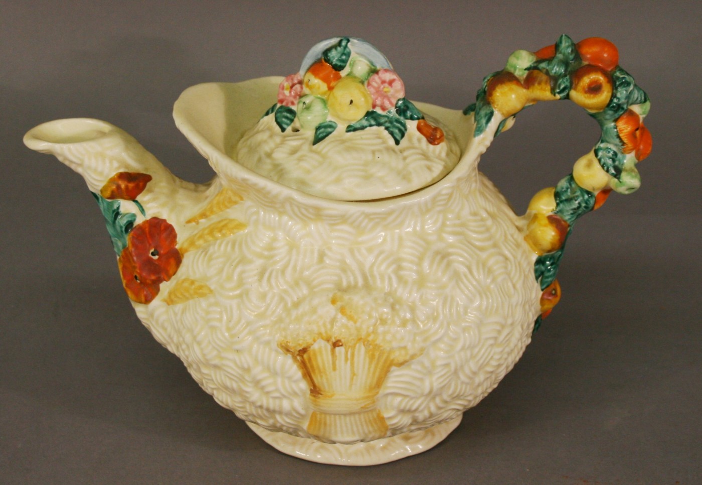 A CLARICE CLIFF NEWPORT POTTERY `CELTIC HARVEST` TEAPOT moulded with harvest produce, printed and