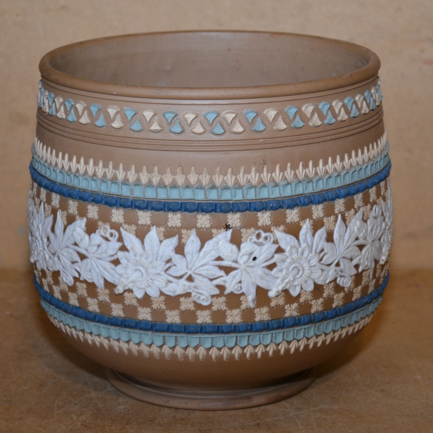 A Royal Doulton Stoneware Bulbous Jardiniere on brown ground with raised white and coloured