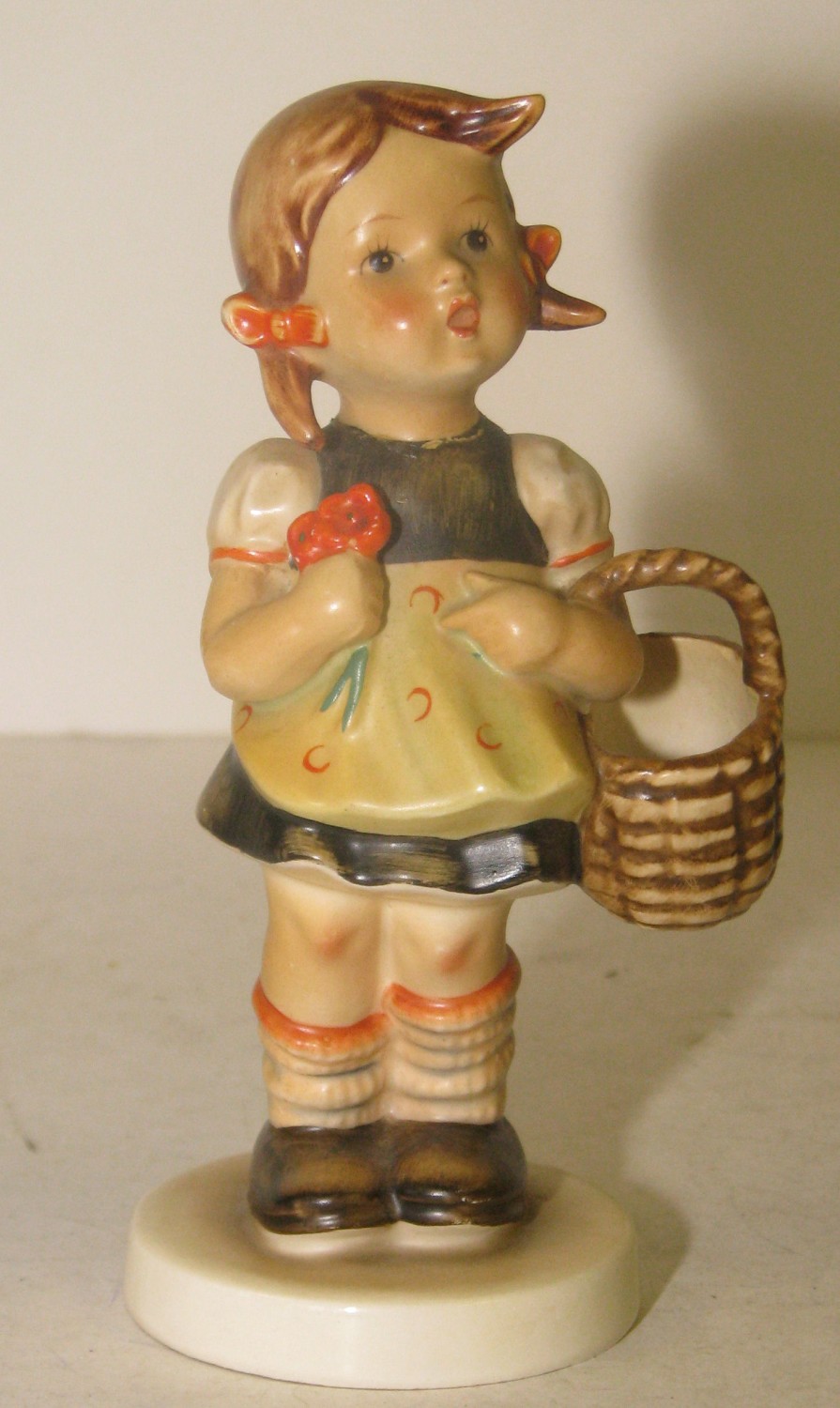 A Goebel Figure of a young girl holding a basket on round base, 15cm high