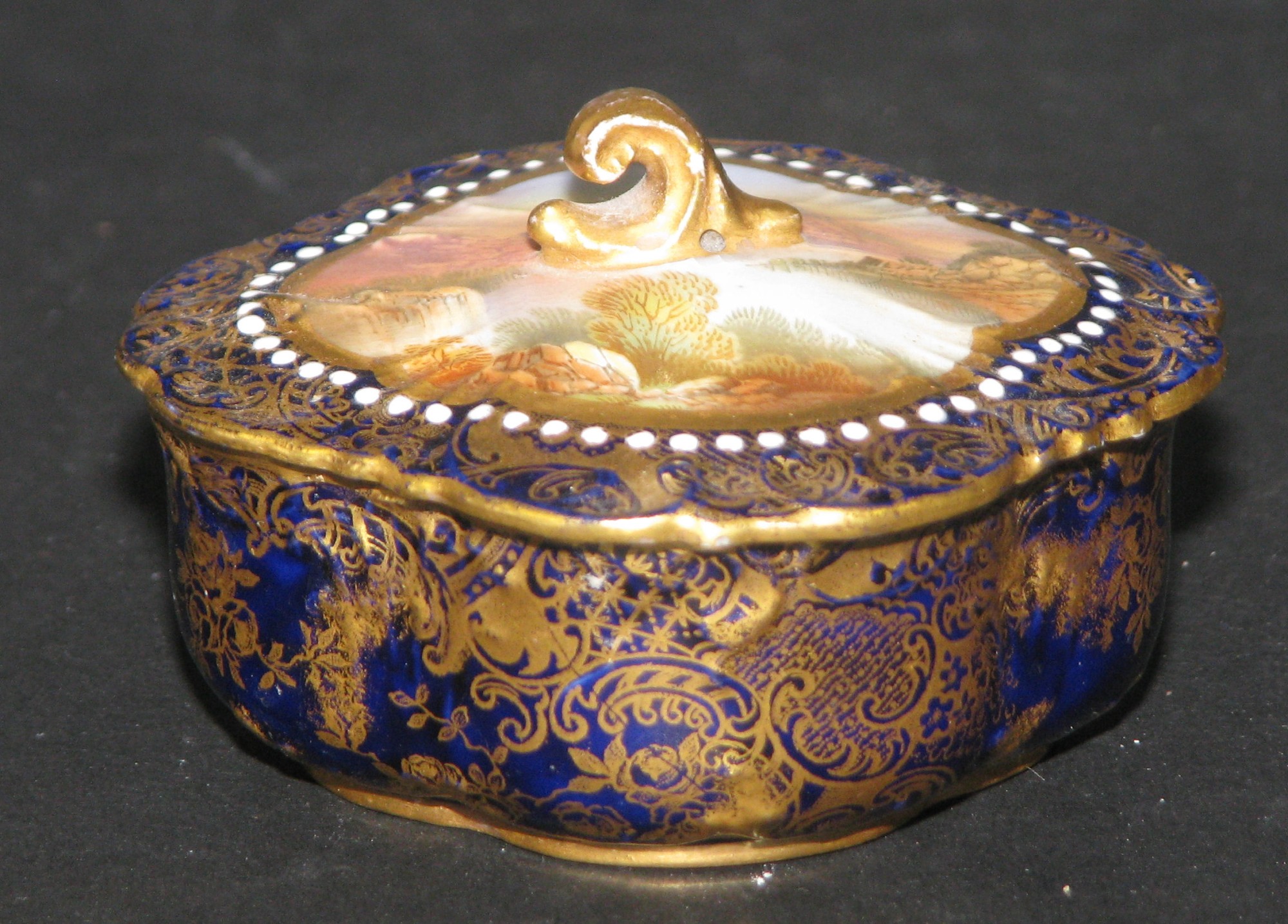 A Limoges Scalloped Lidded Dish on blue ground with river landscape panel and all over gilt