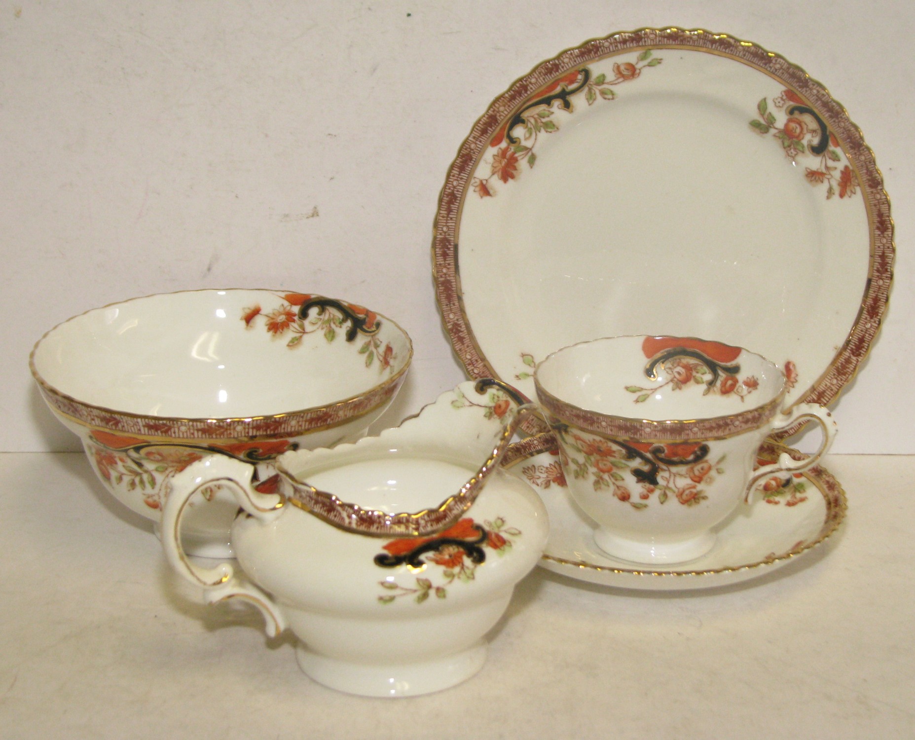 A China Tea Service on white ground with multicoloured floral, leaf, scroll and gilt decoration,