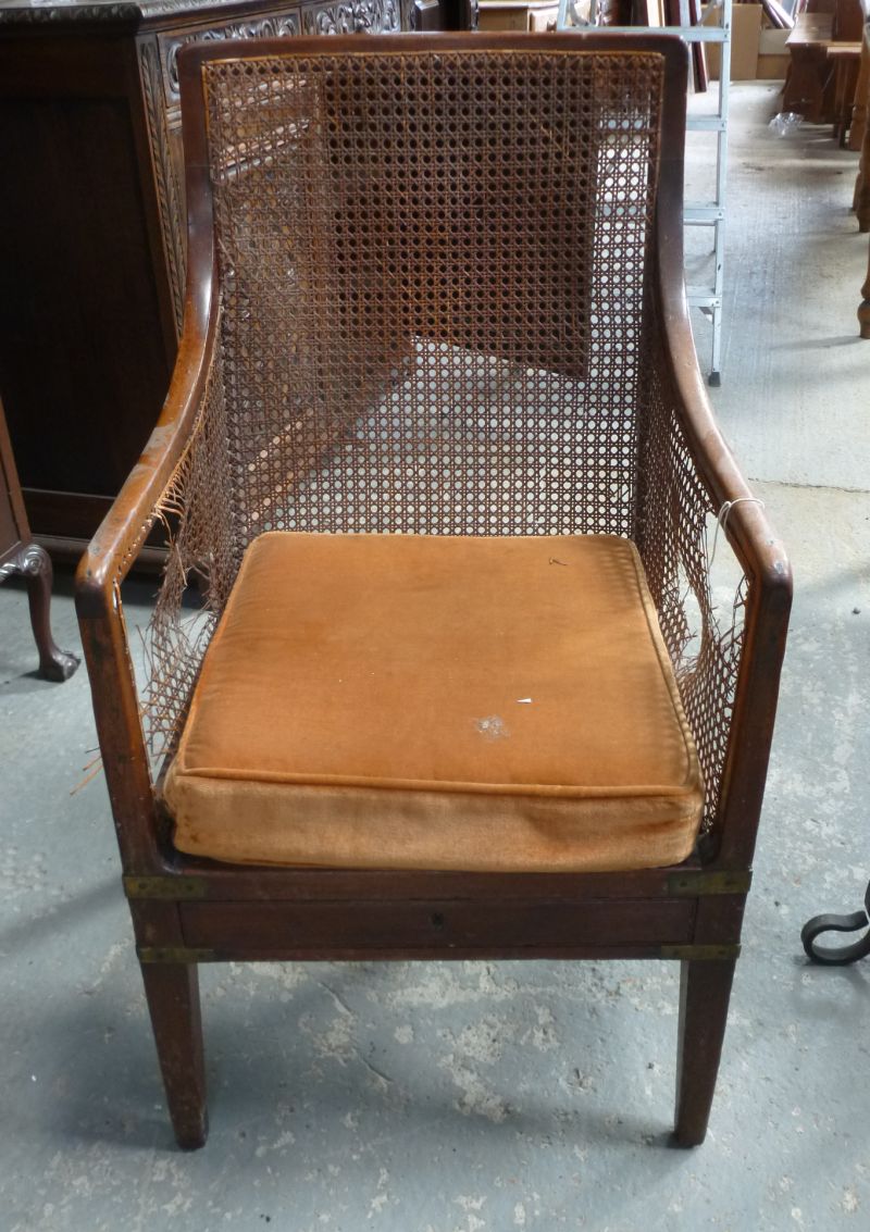 A late 19th/early 20th century brass-bound bergere chair, the shaped top rail with carved back and