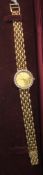 Ladies 14k yellow gold Cyma quartz watch with champagne baton dial, diamond set bezel, on integral