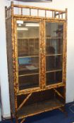 Antique bamboo cabinet fitted with two glazed doors with upper and lower shelves, 90cm wide