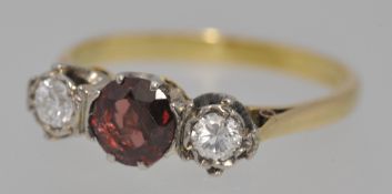 An 18ct three stone ring set with single ruby and two diamonds, size L