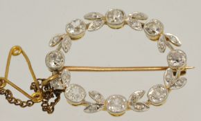 An oval shaped diamond wreath brooch, 28mm long x 24mm wide, comprising surround on 8 cushion shaped
