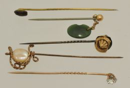 Five yellow metal stick pins including sword design