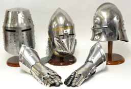 Three reproduction mediaeval armour helmets on display stands together with a pair of armour
