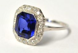A dress ring set with large sapphire style central stone and diamond border