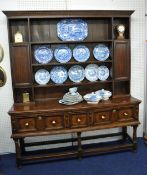 An Antique oak dresser, the upper section with shelves and cupboards, the base with three deep