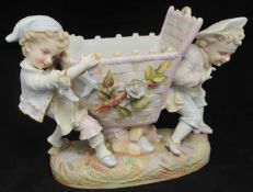 A late 19th century Bisque figure group of two boys with basket and shoes, 25cm high, possibly
