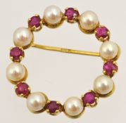 A circular wreath brooch set with pearl and ruby type stones in a yellow 9ct gold mount,