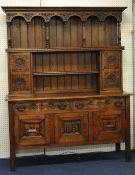 An oak dresser, the upper section with cupboards, two shelves and arcade frieze, the base fitted