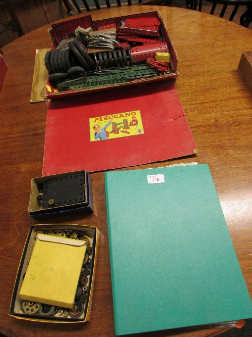 Various Meccano components, including wheels and a clockwork mechanism, with a Meccano cardboard box