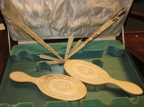 Two ivory dressing table brushes, the backs with intricate foliate carving, and a Chinese style