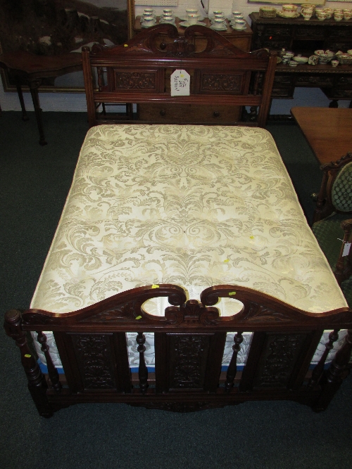 An Edwardian carved red walnut 4`6 bed with broken scroll pediment and box spring base with a