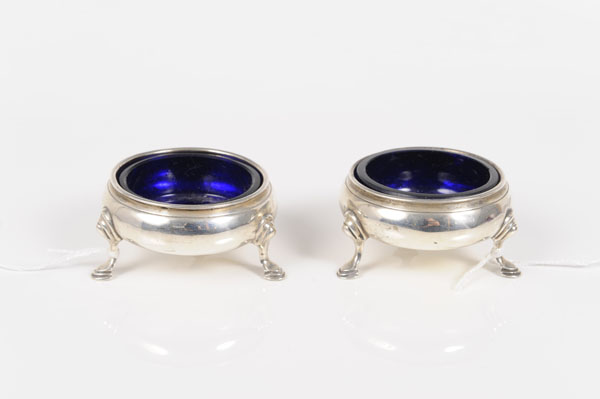 Pair of early George III silver salts of circular form, on three hoof feet with blue glass liners (