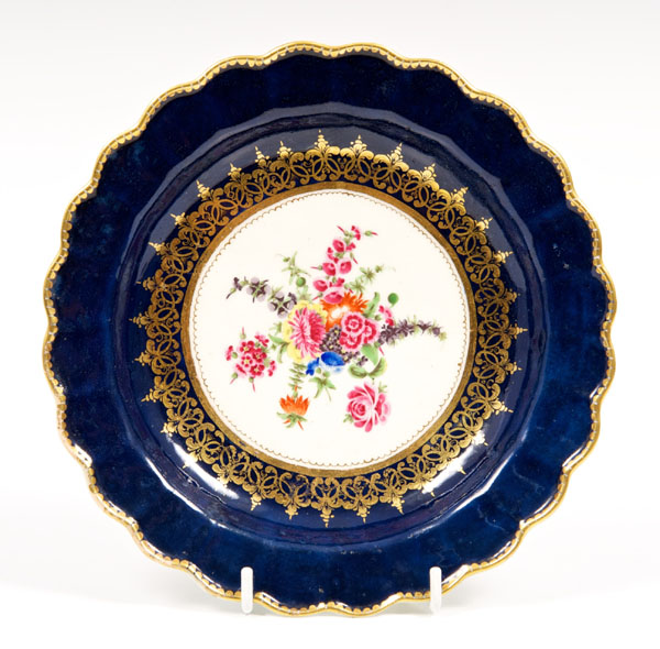 Mid-eighteenth century Worcester fluted plate with polychrome painted floral reserve on gros blue