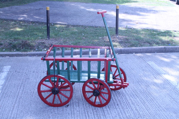 Old red and green painted pull-a-long cart with metal rimmed wooden wheels