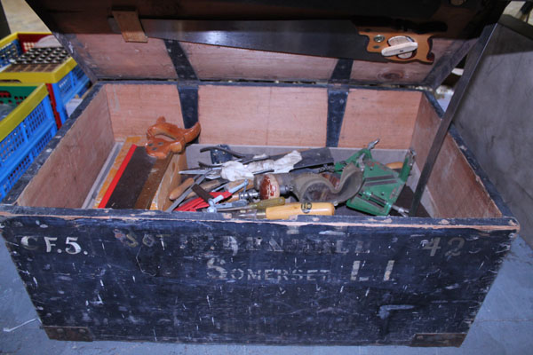 Metal bound chest with two trays containing a selection of miscellaneous tools, including saws,