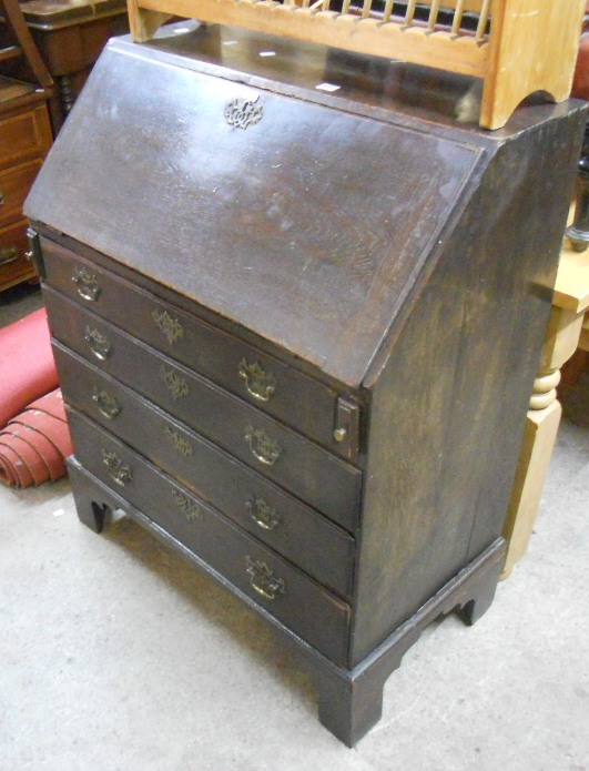 An early 19th Century oak fall-front bureau with fitted interior over four graduated drawers and