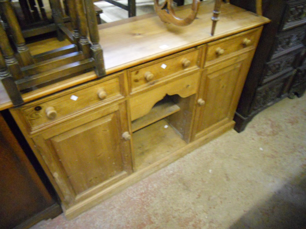 A 4’6” pine three door dresser base, with central pot shelf and two flanking cupboards