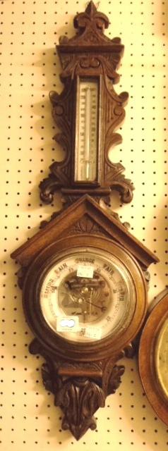 A late Victorian carved oak cased aneroid barometer/thermometer, with visible works