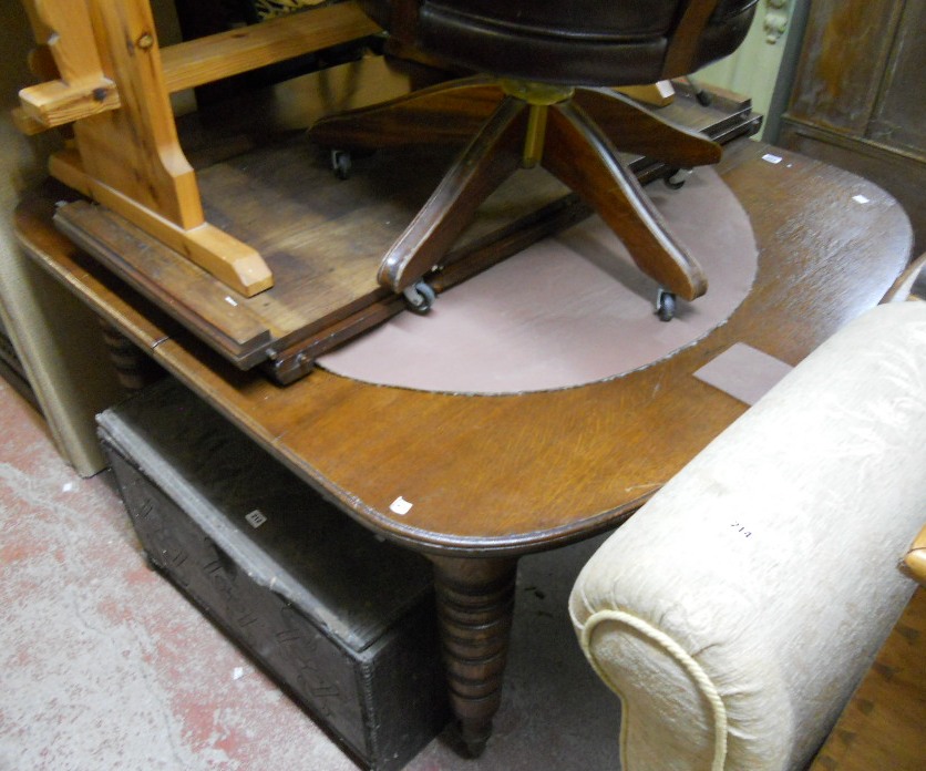 A 4’3” Victorian oak extending dining table on turned legs with brown porcelain casters - with two