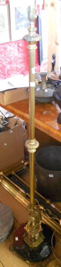 An ornate brass standard lamp on onyx base