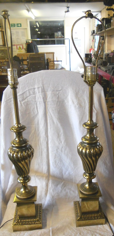 A pair of brass urn shaped table lamps on plinth base