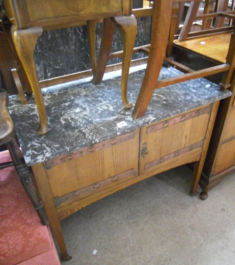 An Arts and Crafts marble topped oak wash stand with decorative beaten copper hinges to doors