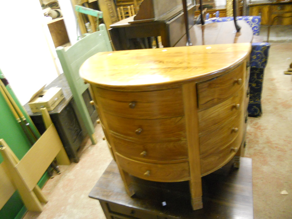 A modern walnut bow fronted chest of twelve drawers