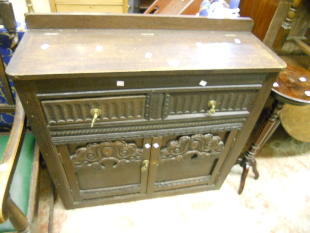 A carved oak sideboard with lift-up top, two drawers and cupboard under