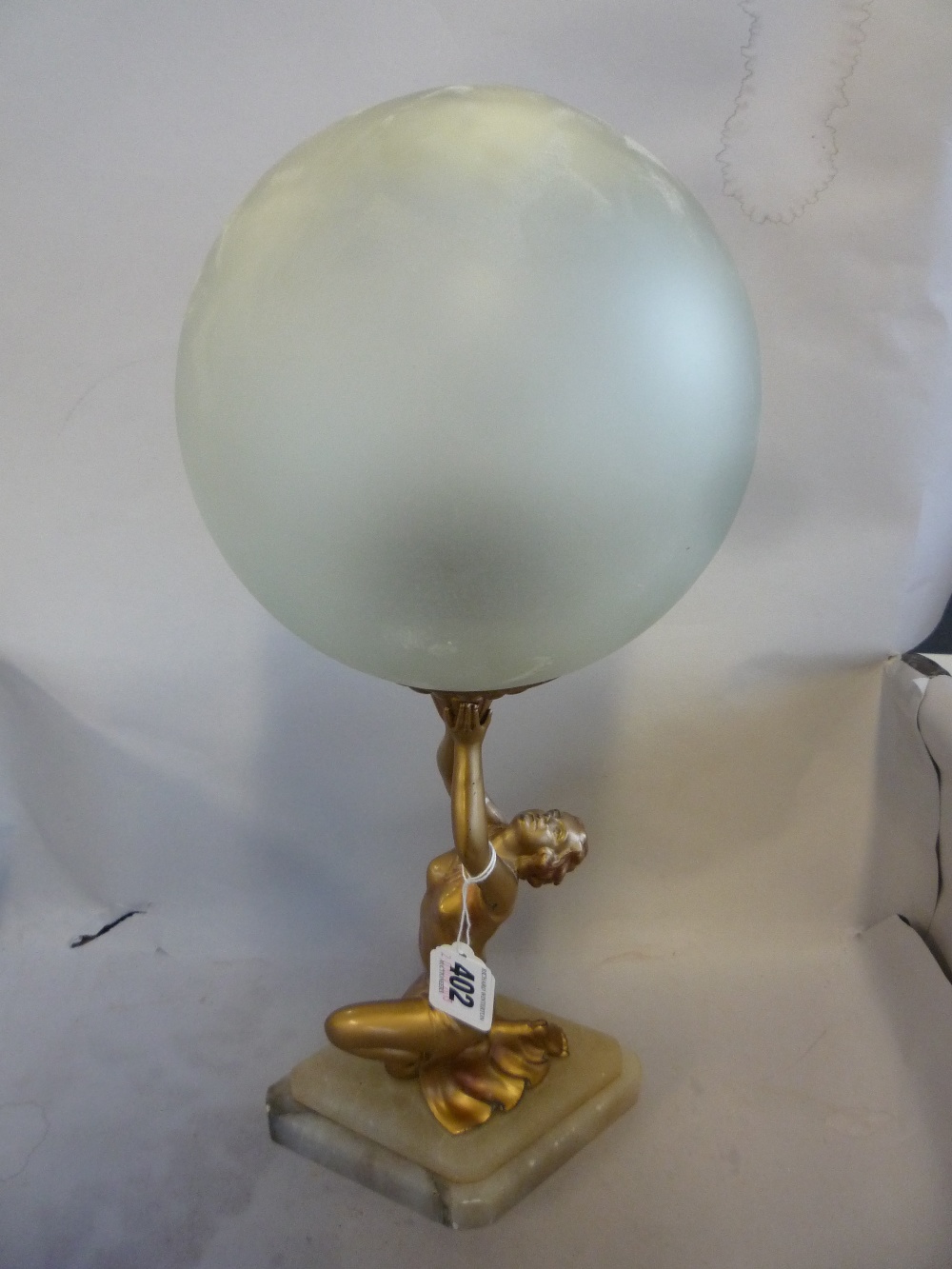 AN ART DECO TABLE LAMP, c.1930`s, gilt metal female figure supporting the frosted glass light shade,
