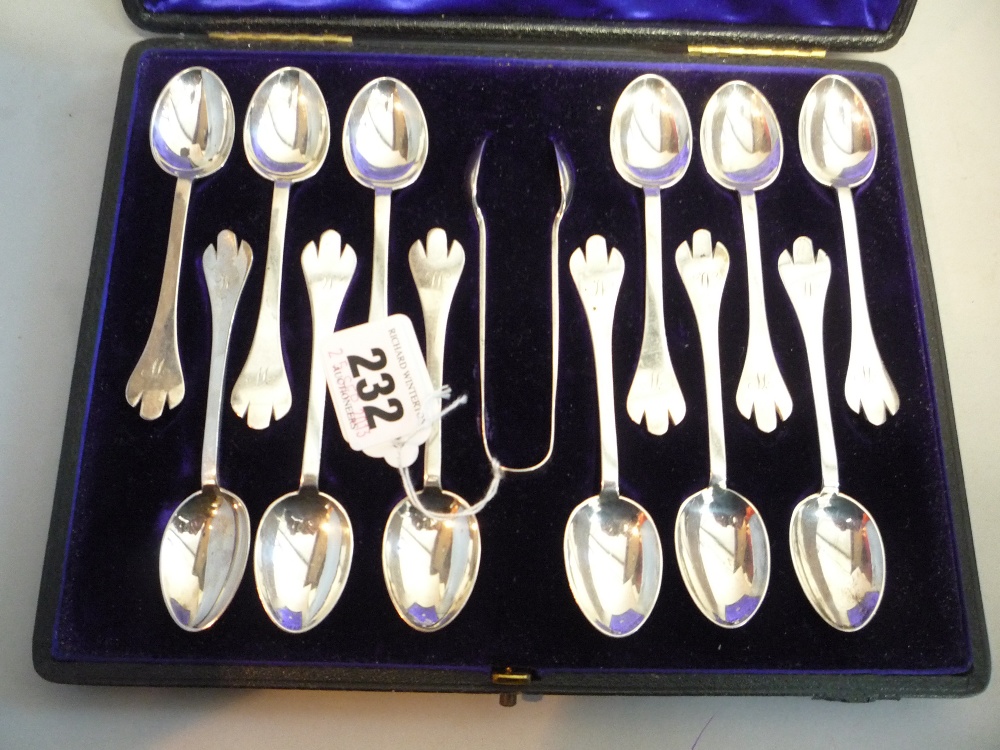 A CASED SET OF TWELVE BRITANNIA TREFOIL FINIAL TEASPOONS/TONGS, (approximately 179g in all)