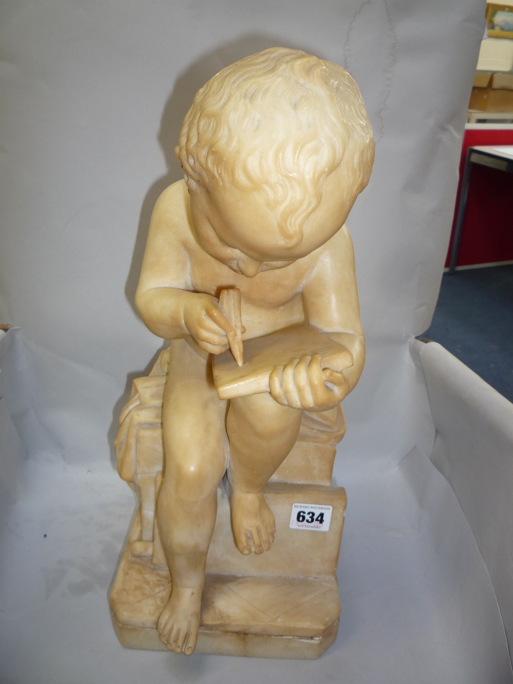 AN ALABASTER STATUE, nude boy on a plinth writing on a tablet, height 42cm