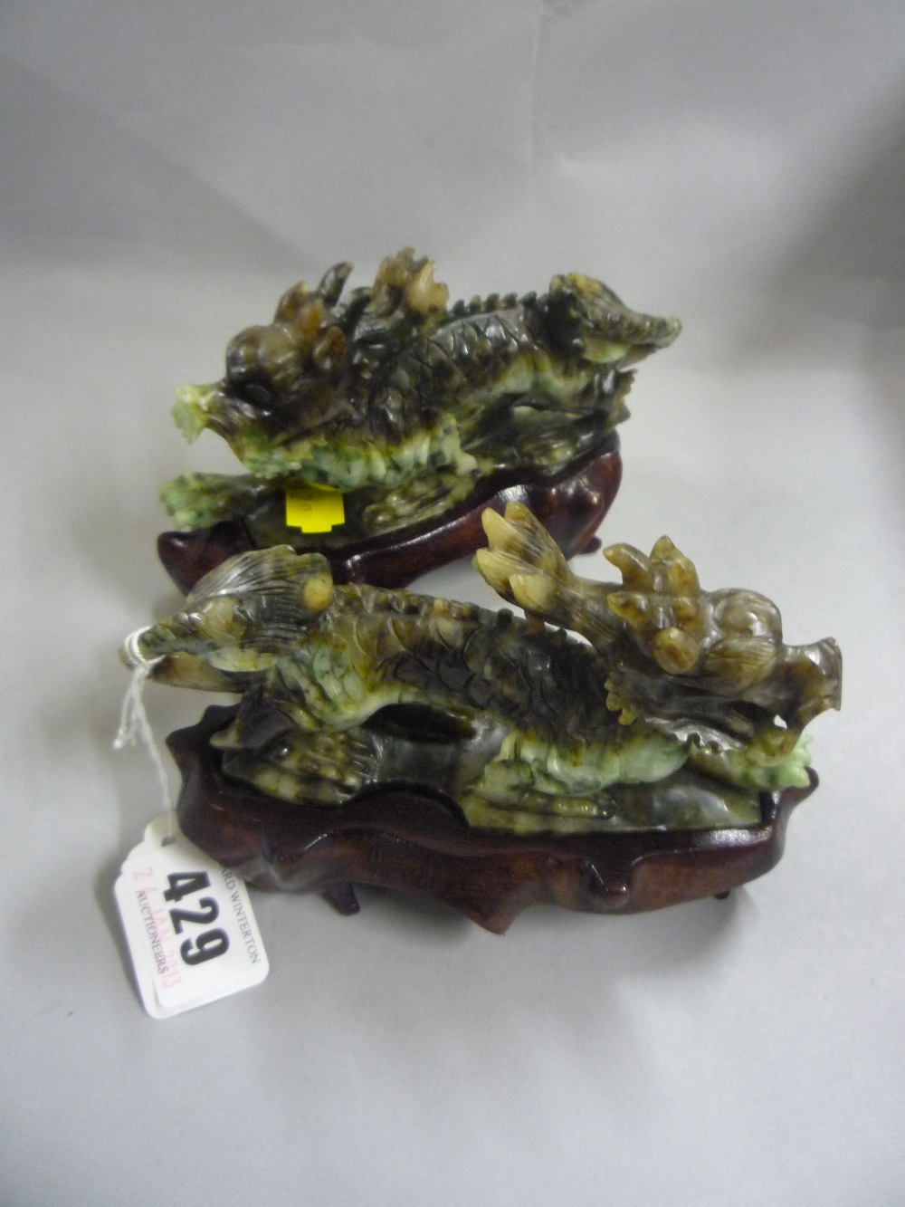 A pair of recent Chinese Moss Jade Dragon Pasant ornaments on wooden stands (2)