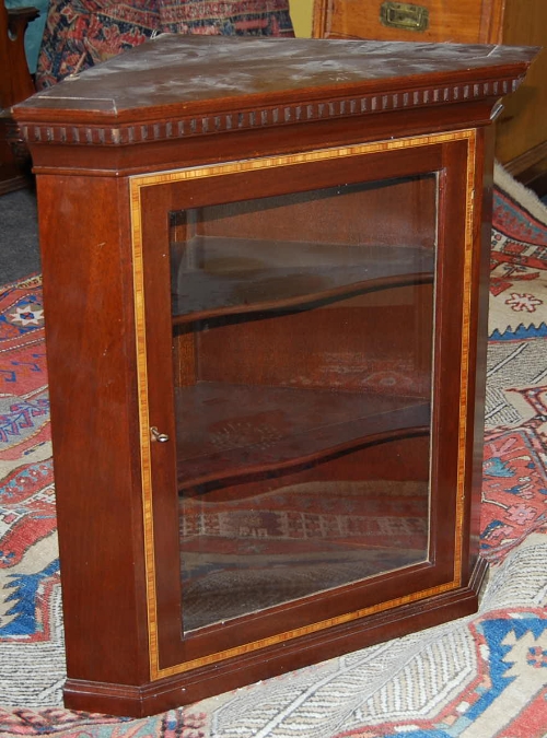 A George III style mahogany hanging corner cupboard, satinwood cross banded, with dentil cornice