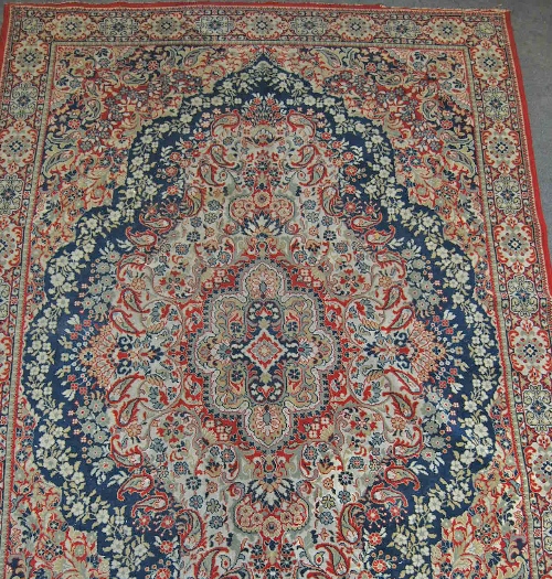 A Tabriz style carpet, the blue quartered field centred with floral motif decorated boteh within