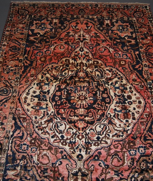 A Heriz carpet with indigo medallion in an ivory panel in a red field with indigo spandrels, 319 x