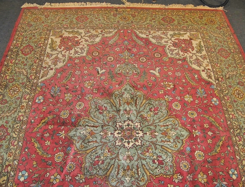 A modern Tabriz style carpet, the red ground quartered field centred with floral lobed motif,