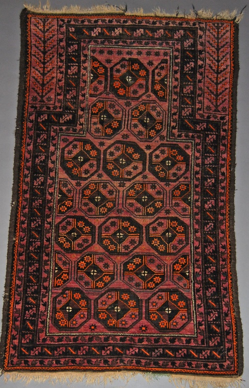 A Turkoman prayer rug with octagons in a faded claret coloured mihrab within serrated leaf border,