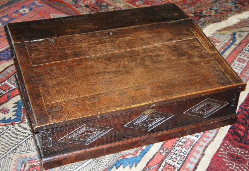 An early 18th Century carved oak scribes desks, the hinged top enclosing a fitted interior, with