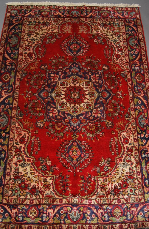 A Heriz rug with flowerhead pole medallion in a red field with flower decorated ivory spandrels