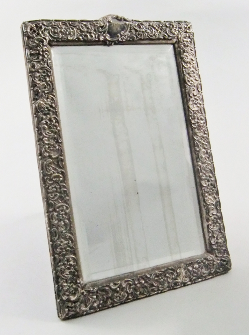 A late 19th century rectangular silver mounted strut mirror with embossed Rococo decoration,