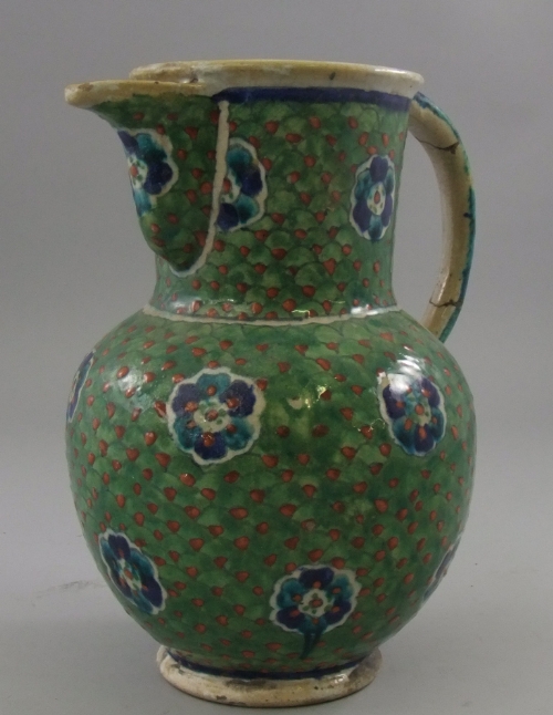 An Iznik style green glazed jug, of classical form with large shaped spout and overall decorated