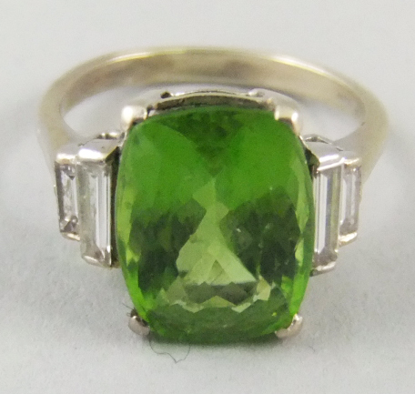 A white metal peridot and diamond set ring, tests as 18ct white gold, the central cushion cut