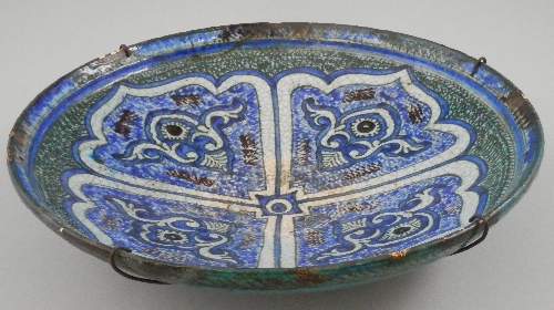 A Persian blue and green glazed pottery charger, 17th century, of circular form and decorated with