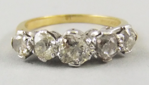 An 18ct gold and diamond set five stone ring, 1 stone cushion cut, colour approx J/K. clarity approx
